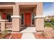 Inviting covered front porch with decorative pillars and red door, complemented by low-maintenance desert landscaping at 5932 Lamotte Ave, Las Vegas, NV 89141