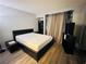 Simple bedroom showcasing a bed, shelving, wood-look floors, and neutral-toned curtains at 6750 Del Rey Ave # 133, Las Vegas, NV 89146