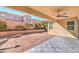 Covered patio with ceiling fan provides shade in the backyard featuring brick pavers and rock landscaping at 7709 Tiny Tortoise St, Las Vegas, NV 89149