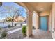 Covered front porch with stone columns and a blue front door at 7709 Tiny Tortoise St, Las Vegas, NV 89149
