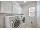 Well-lit laundry room with white cabinets above a side-by-side washer and dryer at 7709 Tiny Tortoise St, Las Vegas, NV 89149