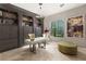 Stylish home office with custom built-ins, decorative chandelier, and a large window overlooking lush greenery at 1212 Muscato Ct, Las Vegas, NV 89144