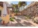 A backyard oasis featuring a stone wall, palm trees, a cozy fire pit, and a private patio at 23 Cerchio Basso, Henderson, NV 89011