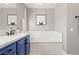 Modern bathroom with a blue vanity, white countertop, and a soaking tub with stylish, geometric tiling at 23 Cerchio Basso, Henderson, NV 89011
