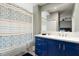 Bright bathroom with a large mirror, blue vanity, white countertop, and a shower with a patterned curtain at 23 Cerchio Basso, Henderson, NV 89011