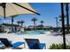 A resort-style pool with lounge chairs, umbrellas, palm trees, and nearby changing rooms for residents at 2765 Frosted Teal Ave, North Las Vegas, NV 89086