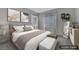 This staged bedroom features warm neutral tones, two windows, and artwork to create a calming space at 3728 White Lion Ln, North Las Vegas, NV 89084