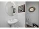A half bathroom features a white vanity sink and round decorative mirror at 537 Blanche Ct, Henderson, NV 89052