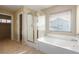 Bright bathroom with a glass shower, soaking tub, and neutral tile flooring at 5861 Lakeland Village Dr, North Las Vegas, NV 89081