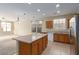 Open-concept kitchen featuring an island, granite counters, wood cabinets, tile flooring, and stainless appliances at 5861 Lakeland Village Dr, North Las Vegas, NV 89081