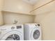Well-lit laundry room features a front-loading washer and dryer with overhead shelf at 5861 Lakeland Village Dr, North Las Vegas, NV 89081