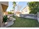 Backyard features mature trees, green grass, lounge furniture, and block wall privacy fencing at 7832 Desert Candle Way, Las Vegas, NV 89128