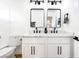 Contemporary dual sink vanity bathroom with black hardware and framed mirrors at 7832 Desert Candle Way, Las Vegas, NV 89128
