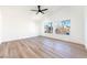 Spacious room with ample light from multiple windows, enhanced by wood-look flooring and ceiling fan at 7832 Desert Candle Way, Las Vegas, NV 89128