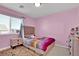 Cozy bedroom with pink walls, a comfortable bed, soft carpet, and a side table with a lamp at 8456 Blackstone Ridge Ct, Las Vegas, NV 89139