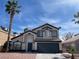 Charming two-story home featuring desert landscaping, a black garage door, and palm tree at 9139 Scallop Reef Ave, Las Vegas, NV 89147
