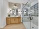 Modern bathroom featuring wood cabinets, double vanity, and glass-enclosed shower with glass block window at 9524 Chalgrove Village Ave, Las Vegas, NV 89145