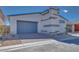 A modern home featuring a two car garage, gray door, and desert landscaping at 990 Golden Summit Dr, Las Vegas, NV 89138