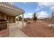 View of backyard with covered patio, desert landscaping, and a mature shade tree at 9917 Arbuckle Dr, Las Vegas, NV 89134