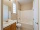 A bathroom with white tiling in the shower/bath, and a standard toilet and sink with wood cabinetry at 10051 Sand Key St, Las Vegas, NV 89178