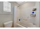 Tiled bathtub with shower in a bright bathroom with window and white fixtures at 10722 Red Badge Ave, Las Vegas, NV 89166