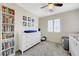 Neutral bedroom features a bookcase, dresser, ceiling fan, plantation shutters and a cozy grey chair at 10722 Red Badge Ave, Las Vegas, NV 89166