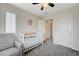 Bright bedroom featuring a white crib, a soft grey chair, and a ceiling fan with light at 10722 Red Badge Ave, Las Vegas, NV 89166