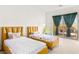 Bright bedroom showcasing two beds with colorful bedspreads and access to outdoor patio at 10879 Artesano Ave, Las Vegas, NV 89135