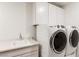 Clean laundry room featuring a utility sink and modern, front loading washer and dryer set at 10879 Artesano Ave, Las Vegas, NV 89135