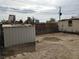 View of the backyard showing a storage shed set on the dirt. Buildings are visible behind the fencing at 110 Palm Ln, Las Vegas, NV 89101