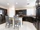 Kitchen featuring dark cabinetry, stainless steel appliances, breakfast bar, and sleek countertops at 1309 Rainy Sky Ave, North Las Vegas, NV 89030