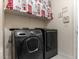 A modern laundry room with a black washer and dryer, and white shelving at 1309 Rainy Sky Ave, North Las Vegas, NV 89030