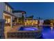 A nighttime view of the pool featuring the hot tub, covered patio, and manicured landscaping at 2001 Alcova Ridge Dr, Las Vegas, NV 89135