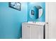 Powder room featuring bright blue paint, a round mirror, and a modern vanity with white cabinets at 2419 Country Orchard St, North Las Vegas, NV 89030
