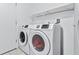 A bright laundry room with modern, front-loading washer and dryer and white walls at 2419 Country Orchard St, North Las Vegas, NV 89030