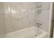 Crisp white tub and shower with marble style tiling and chrome fixtures at 3821 1/2 Daisy St # 25, Las Vegas, NV 89119