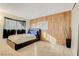 Bedroom with a leather platform bed, wood accent wall, and bright, neutral carpet at 3821 1/2 Daisy St # 25, Las Vegas, NV 89119