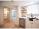 Kitchen with stainless steel dishwasher, floating shelves, black faucet, and white cabinets at 3823 S Maryland Pkwy # L6, Las Vegas, NV 89119