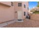 Side yard of a townhome, featuring stucco walls, a metal security door, and low-maintenance desert landscaping at 5382 Runningbrook Rd, Las Vegas, NV 89120