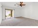 Sunlit bedroom featuring neutral carpet, ceiling fan, and sliding door to the backyard at 5912 Cuddles Ct, North Las Vegas, NV 89081