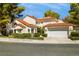 View of exterior elevation with clay tile roof, two-car garage and mature trees at 6923 Emerald Springs Ln, Las Vegas, NV 89113
