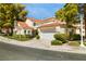 Charming exterior featuring a clay tile roof, two-car garage, and lush, mature trees at 6923 Emerald Springs Ln, Las Vegas, NV 89113