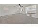 An empty living room with neutral carpeting, bright white walls, and a view into the kitchen and dining area at 7200 Mineral Park Ave, Las Vegas, NV 89179
