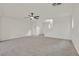 A large, empty living room with carpet, white walls, a ceiling fan, and staircase access at 7200 Mineral Park Ave, Las Vegas, NV 89179