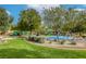 Community playground featuring slides and a splashpad with lush green grass and mature trees at 7579 Harwich Bay Ave, Las Vegas, NV 89179