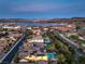 Panoramic aerial view of a home in a golf course community with lake and mountain views at sunset at 79 Rezzonico Dr, Henderson, NV 89011