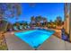 Beautifully lit pool and spa with cozy seating areas and lush landscaping, perfect for evening relaxation at 79 Rezzonico Dr, Henderson, NV 89011