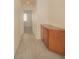 Hallway featuring wood-look tile flooring and a wooden cabinet with doors, leading to a bedroom with neutral carpeting at 9323 W Rochelle Ave, Las Vegas, NV 89147