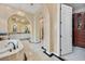 Elegant bathroom featuring a soaking tub, tiled walls, decorative lighting, and arched doorways at 104 N Royal Ascot Dr, Las Vegas, NV 89144