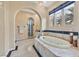 Bathroom featuring a tub with tile surround, arched doorway, and a window with blue valance at 104 N Royal Ascot Dr, Las Vegas, NV 89144